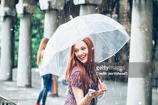 glückliche junge frau fuß mit regenschirm unter regen - rain model stock-fotos und bilder