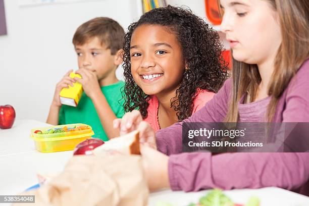 diverse elementary students eat lunch in classroom - juice box stock pictures, royalty-free photos & images
