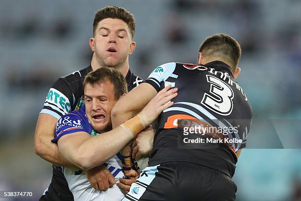 Chad Townsend and Jack Bird of the Sharks tackle Josh Morris of the Bulldogs during the round 13 NRL match between the Canterbury Bulldogs and the...