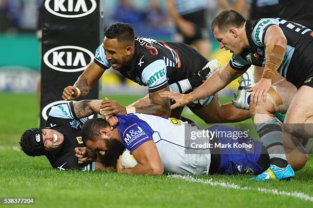 Michael Ennis, Ben Barba and Paul Gallen of the Sharks fail to stop Sam Kasiano of the Bulldogs as he scores a try during the round 13 NRL match...