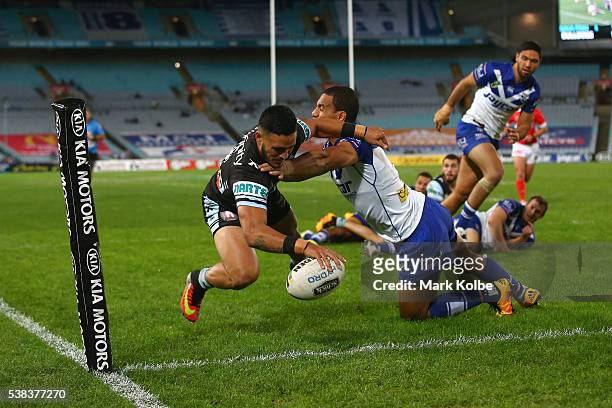 Valentine Holmes of the Sharks scores a try as he is tackled by William Hopoate of the Bulldogs during the round 13 NRL match between the Canterbury...