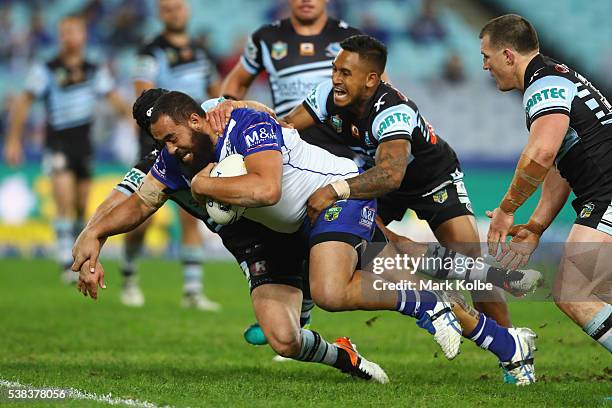 Michael Ennis, Ben Barba and Paul Gallen of the Sharks fail to stop Sam Kasiano of the Bulldogs as he scores a try during the round 13 NRL match...