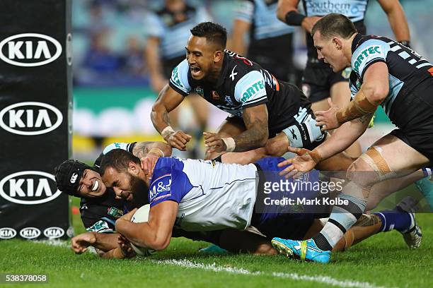 Michael Ennis, Ben Barba and Paul Gallen of the Sharks fail to stop Sam Kasiano of the Bulldogs as he scores a try during the round 13 NRL match...