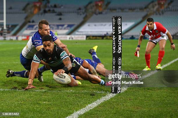 Ricky Leutele of the Sharks scores a try as he is tackled by Josh Reynolds and Sam Perrett of the Bulldogs during the round 13 NRL match between the...