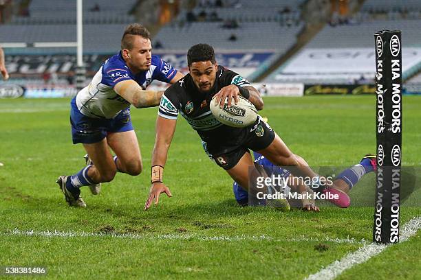 Ricky Leutele of the Sharks scores a try as he is tackled by Josh Reynolds and Sam Perrett of the Bulldogs during the round 13 NRL match between the...