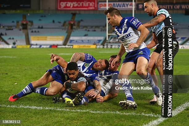 Ricky Leutele of the Sharks is tackled short of the line by Craig Garvey and Joshua Jackson of the Bulldogs during the round 13 NRL match between the...