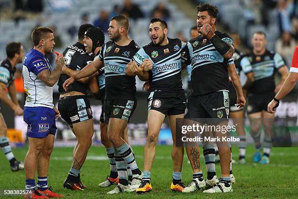 Craig Garvey of the Bulldogs looks dejected as Valentine Holmes, Michael Ennis, Wade Graham, Jack Bird and Andrew Fifita of the Sharks celebrate...