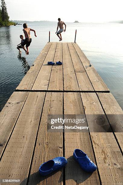 tre ragazzi saltare in lago superiore, parco nazionale dell'isola reale - minnesota v michigan foto e immagini stock