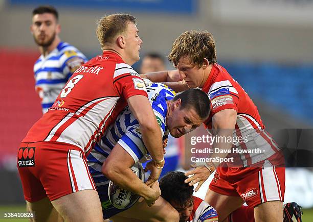 Wigan Warriors' Joel Tomkins is tackled by brother Salford Red Devils' Logan Tomkins and Craig Kopczak during the First Utility Super League Round 17...