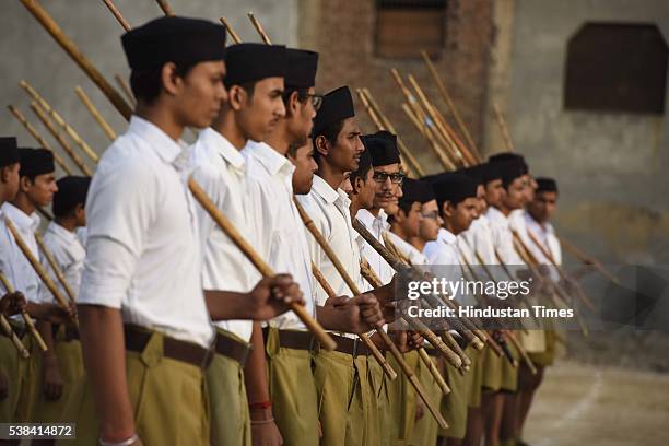 Rashtriya Swayamsevak Sangh volunteers hold sticks as they pray during a RSS Volunteer Training Camp at Gandhi Nagar on June 6, 2016 in New Delhi,...