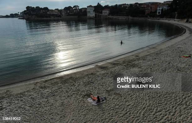 Woman lays down on the beach while another one swims in the sea in Bandol, southeastern France, on June 6, 2016.