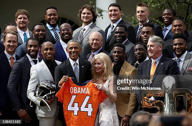 President Barack Obama holds up a Denver Broncos jersey presented to him as a gift by Annabel Bowlen, wife of Broncos majority owner Pat Bowlen,...