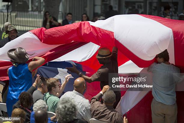 People gather a flag that accidentally fell on the crowd before the South Los Angeles Get Out The Vote Rally for Democratic presidential candidate...