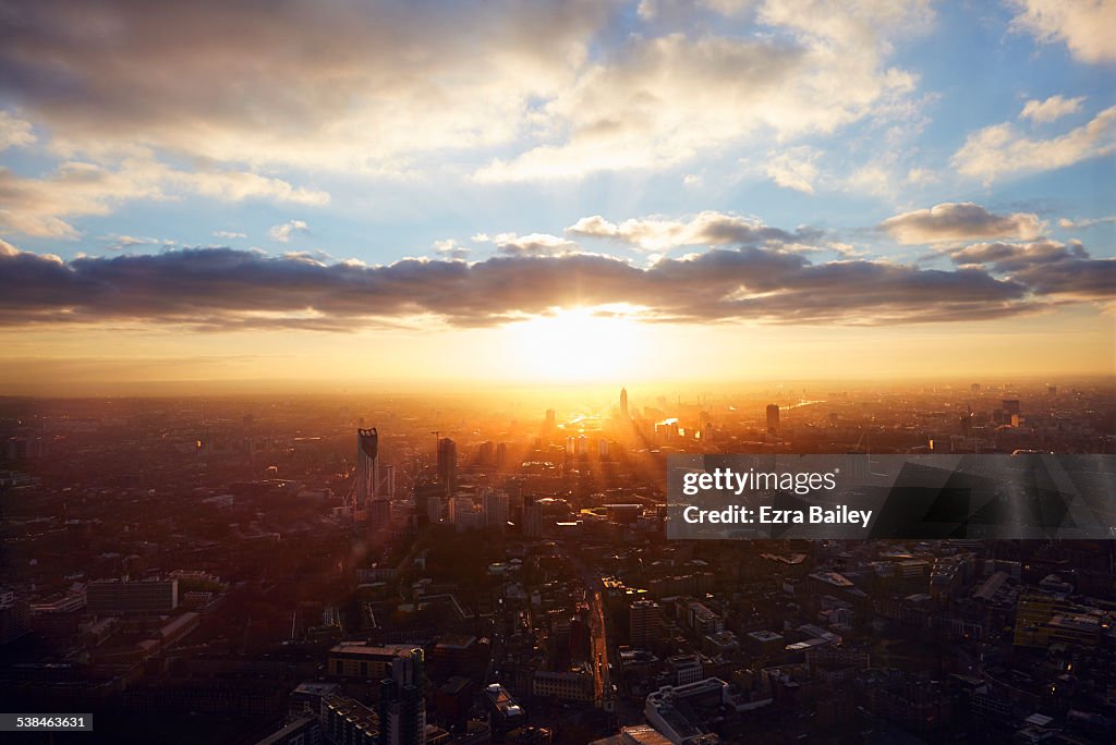 The sun rises through the city on a misty morning.