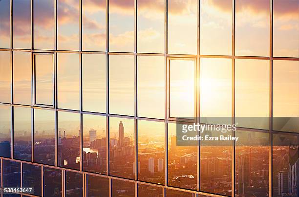 the city at sunrise reflected in a sky scraper. - reflection photos et images de collection