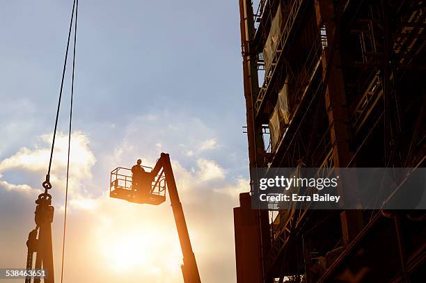 construction worker silhouetted by a sunset. - crane construction machinery stock-fotos und bilder