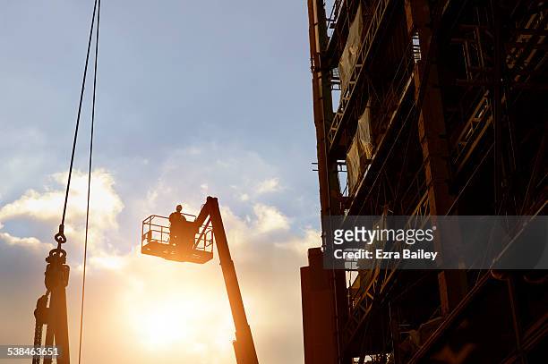 construction worker silhouetted by a sunset. - built structure fotografías e imágenes de stock