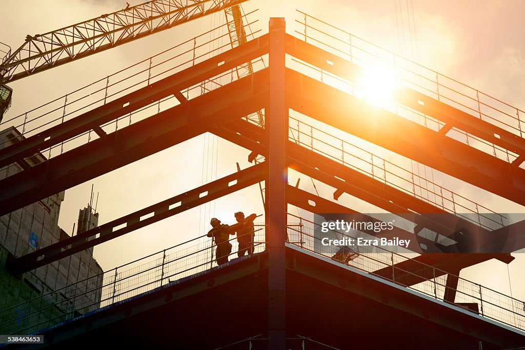 Construction workers silhouetted against the sun