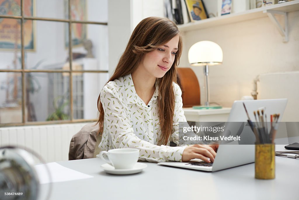 Young creative woman typing on laptop