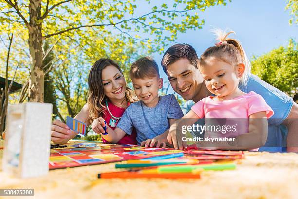glückliche familie, die ein tag im freien und spielen brettspiel. - familie brettspiel stock-fotos und bilder