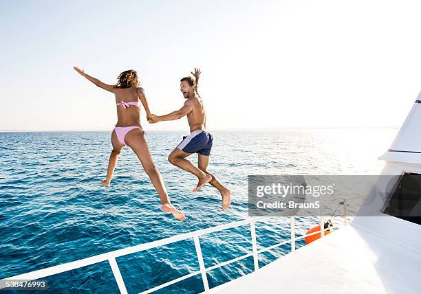 allegra coppia saltando da barca. - jumping of boat foto e immagini stock