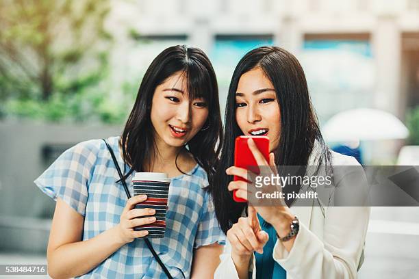 日本のガールフレンドを見ている、スマートフォン - 若い カワイイ 女の子 日本人 ストックフォトと画像