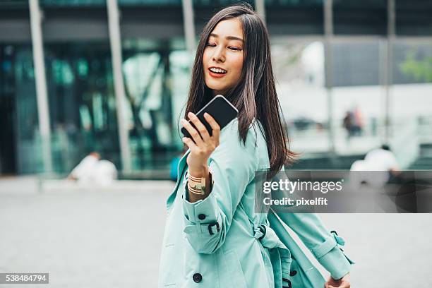 young asian ethnicity woman with smart phone - smart casual walking stock pictures, royalty-free photos & images