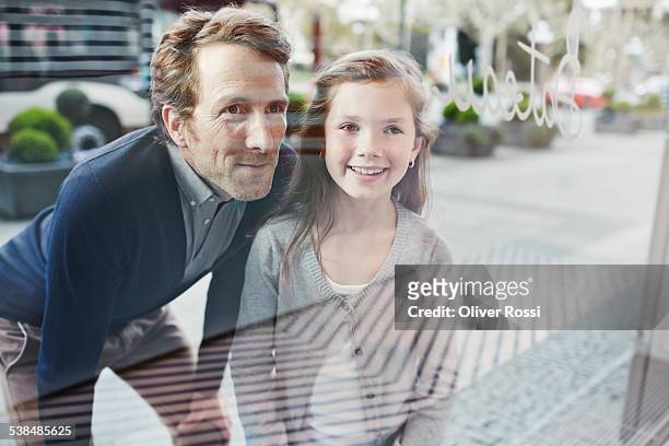 smiling father and daughter looking at shop window - store window stock pictures, royalty-free photos & images