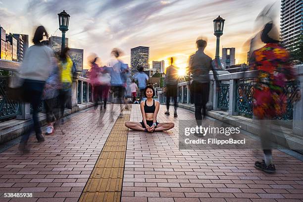 frau meditieren in der menge während dem sonnenuntergang - blurry city stock-fotos und bilder