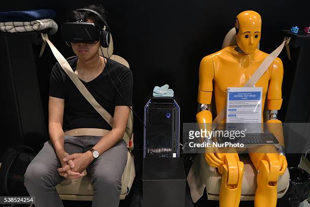 Visitor takes part in a virtual test drive using special glasses next to a crash test dummy at the Toyota show room in Tokyo, Japan, June 6, 2016.