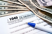 1040 Individual tax return form close-up with pen and dollars