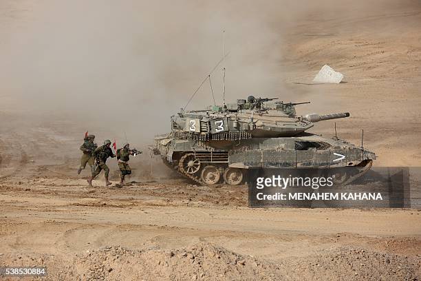 Israeli soldiers run next to an Israeli tank during a joint army drill which includes infantry, aviation, tanks and artillery units in the army...
