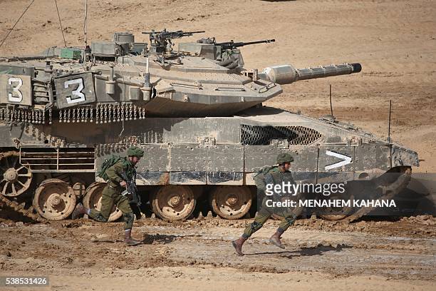 Israeli soldiers run next to a tank during a joint army drill which includes infantry, aviation, tanks and artillery units in the army training base...