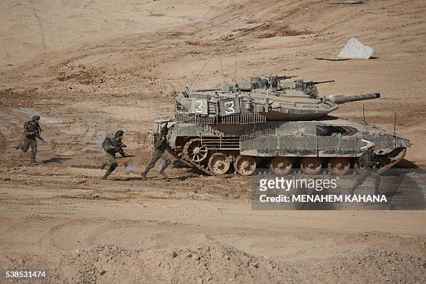 Israeli soldiers run next to a tank during a joint army drill which includes infantry, aviation, tanks and artillery units in the army training base...