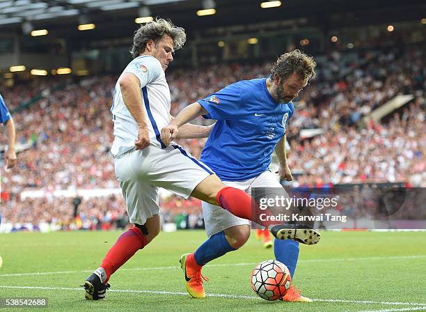 Michael Sheen gets tackled by John Bishop during Soccer Aid 2016 at Old Trafford on June 5, 2016 in Manchester, United Kingdom.