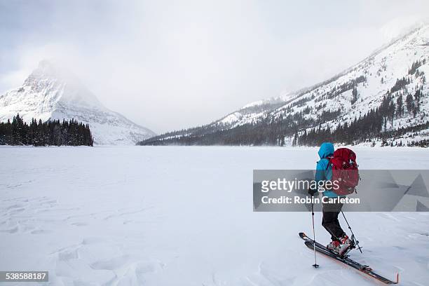 a woman skiing on two medicine lake in front of sinopah mountain in glacier national park, montana. - two medicine lake montana stockfoto's en -beelden
