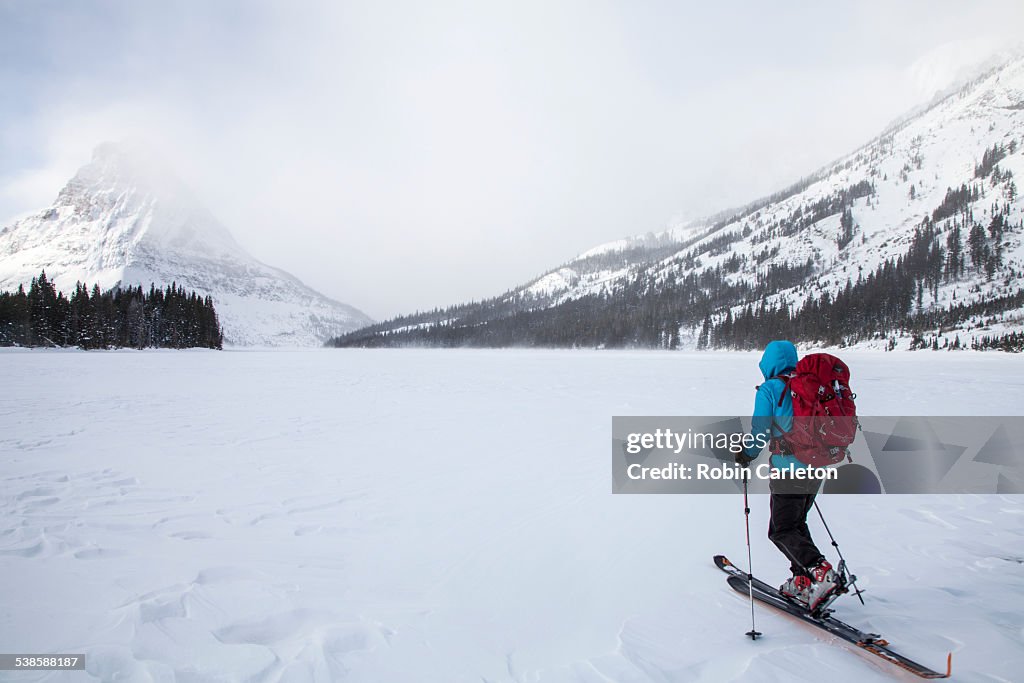 A woman skiing on Two Medicine Lake in front of Sinopah Mountain in Glacier National Park, Montana.