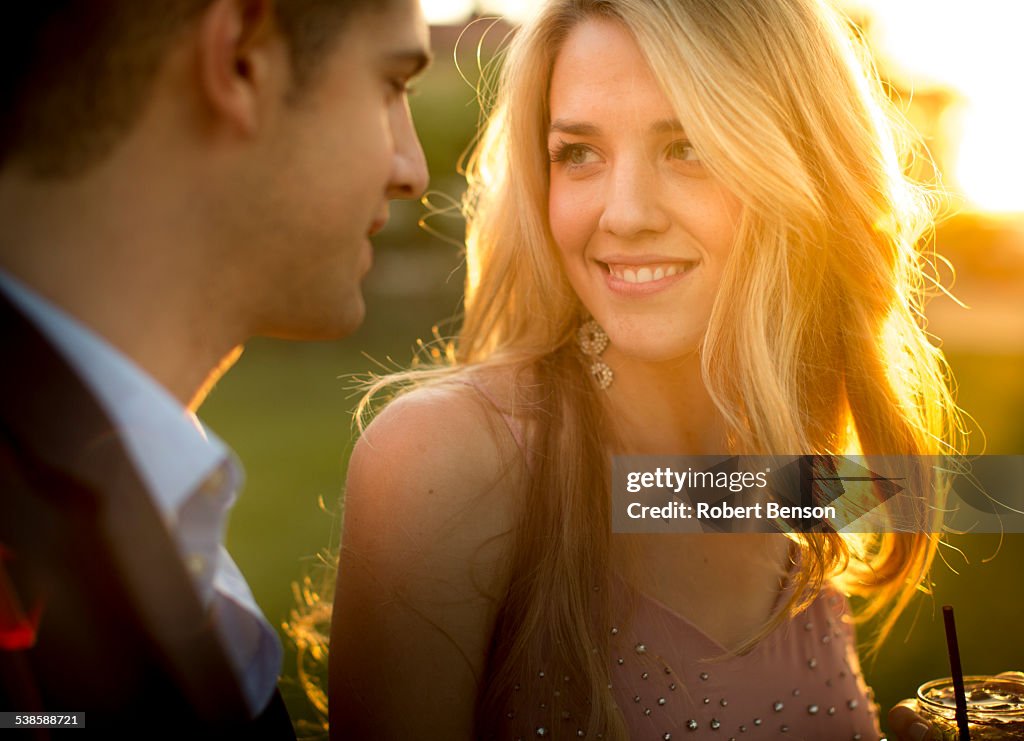 A pretty young girl stares at the eyes of a smart young man stands close to her.