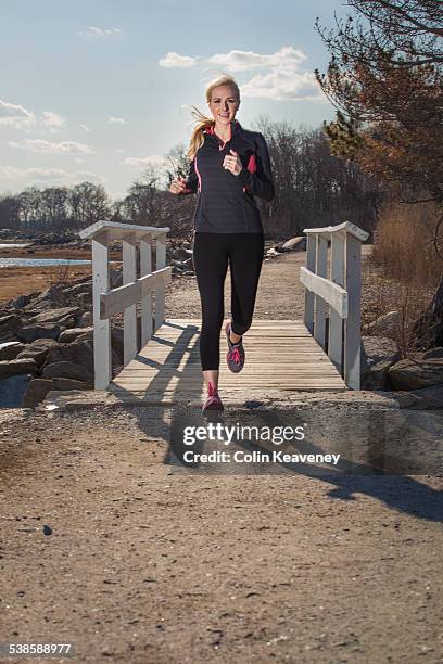 a woman enjoys a run down a seaside path. - greenwich connecticut stock pictures, royalty-free photos & images