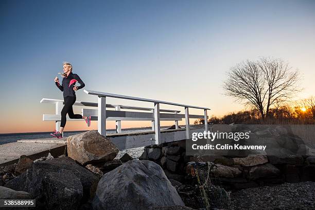 a runner crosses a seaside bridge at sunset. - greenwich connecticut stock pictures, royalty-free photos & images