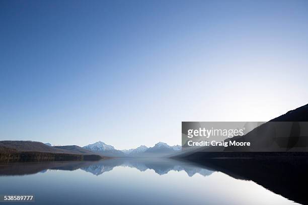 a calm morning before sunrise on lake mcdonald in glacier national park. - lake horizon stock pictures, royalty-free photos & images