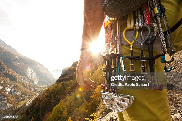 various climbing gear including friends and nuts hanging on a climbers harness, backlit by the sun. cadarese, ossola, italy. - bergbeklimartikelen stockfoto's en -beelden