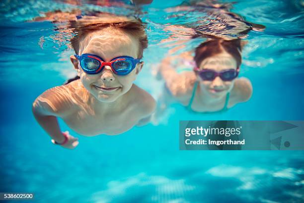 glückliche kinder schwimmen unter wasser im pool - swimming stock-fotos und bilder