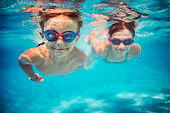 Happy kids swimming underwater in pool