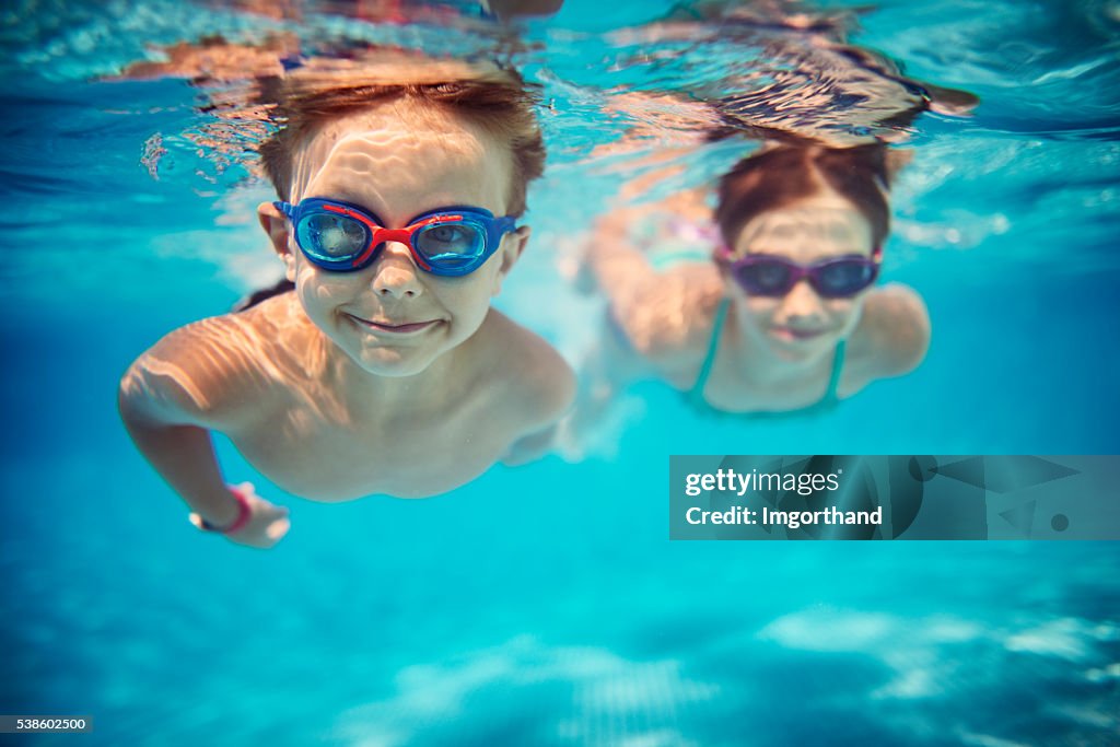 Happy kids swimming underwater in pool