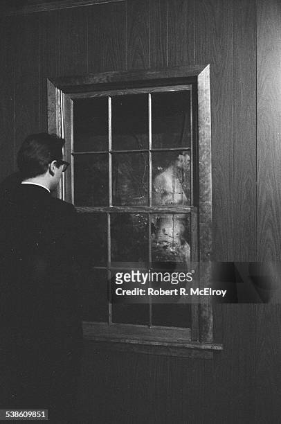 An unidentified man looks at a naked woman through a window installation during '9 Evenings: Theatre & Engineering,' New York, New York, between...