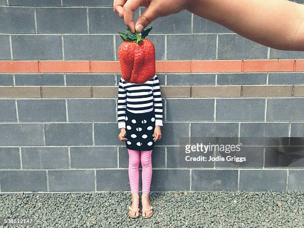 Child with large strawberry in front of face