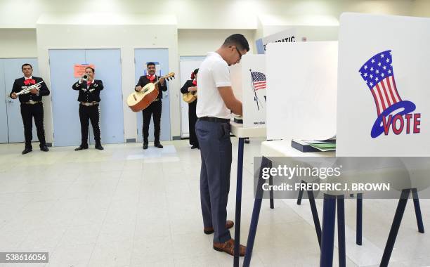 First time voter Victor Rodriguez is serenaded by a Mariachi band while casting his vote at a polling station in Cudahy, California on June 7, 2016.