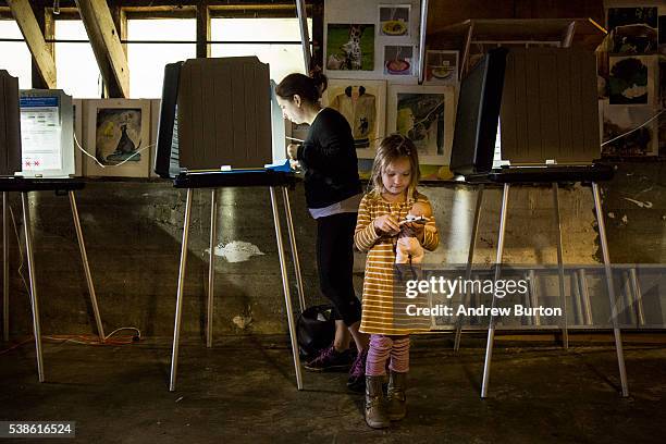 Joy Alferness votes in the California primaries while her daughter, Eden Alferness, age 5, plays on a phone, on June 7, 2016 in the Potrero hill...