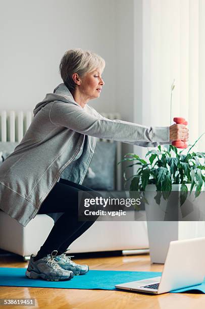 mature woman exercising at home. - crouching stock pictures, royalty-free photos & images